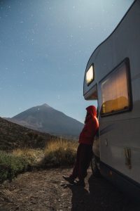 Man near camper van on hill at night