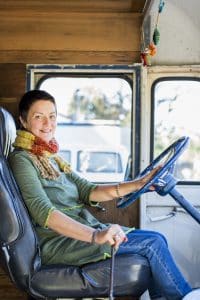 Portrait of mature hippy woman in driving seat of camper van
